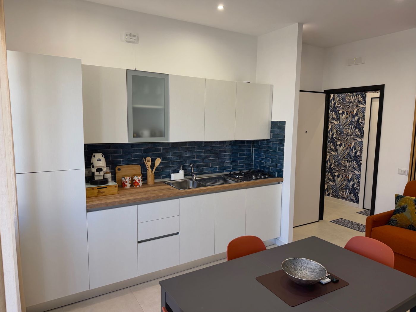 Cucina completa con frigorifero, forno, piano cottura e piastrelle blu