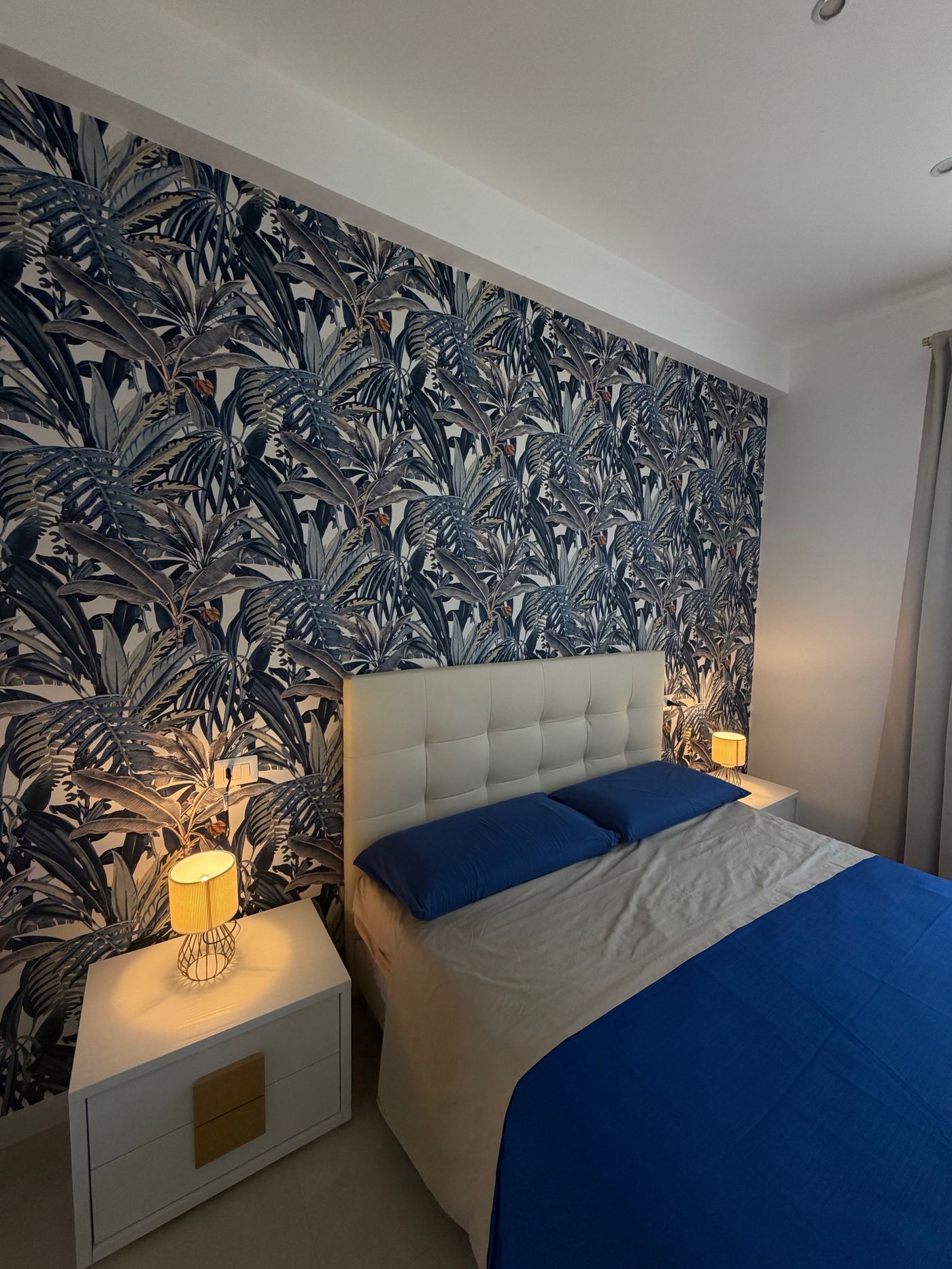 Letto matrimoniale e comodino con lampada dorata accesa