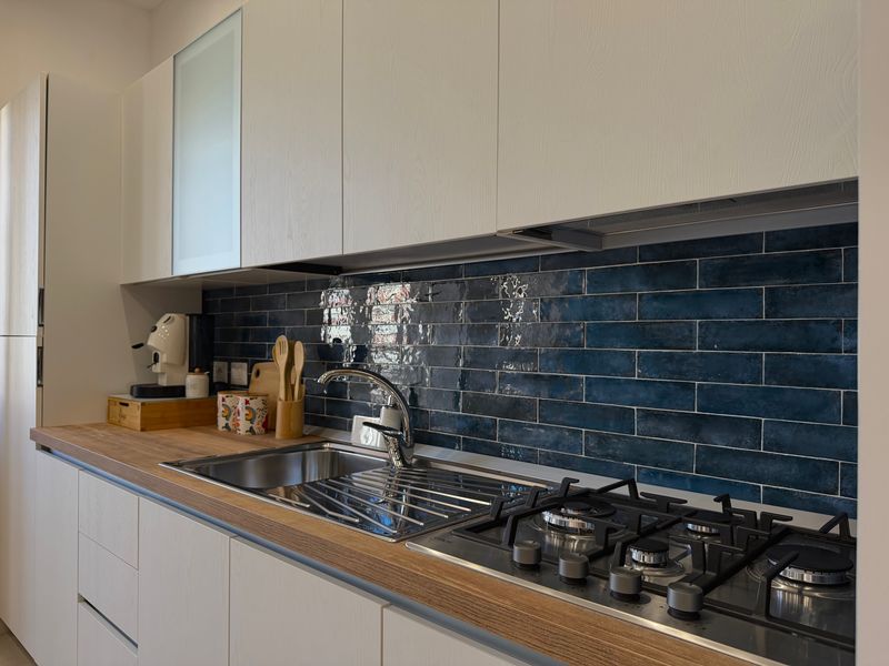 Piano cottura e lavello con le piastrelle blu lucide della cucina